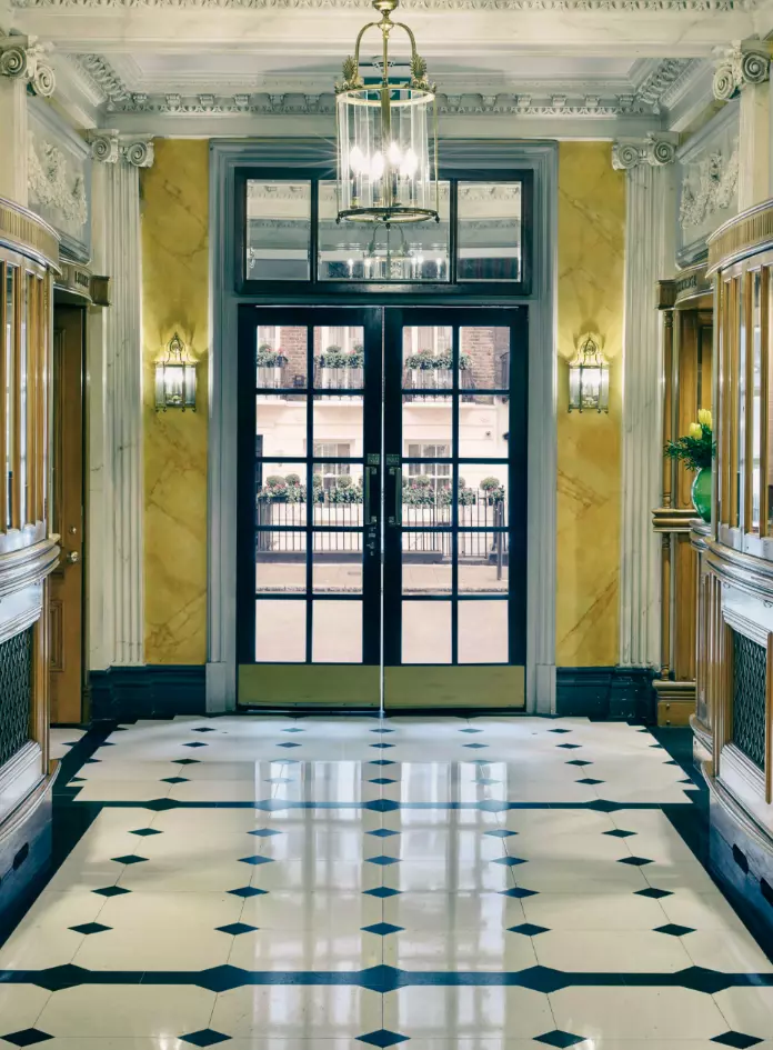 Entrance lobby to 47 Park Street in London, England, with shiny black and white walkway tiles and gold and cream wall accents