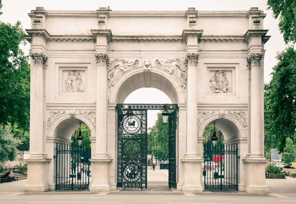 Ornate, carved white marble victory arch in London, with black wrought iron gates