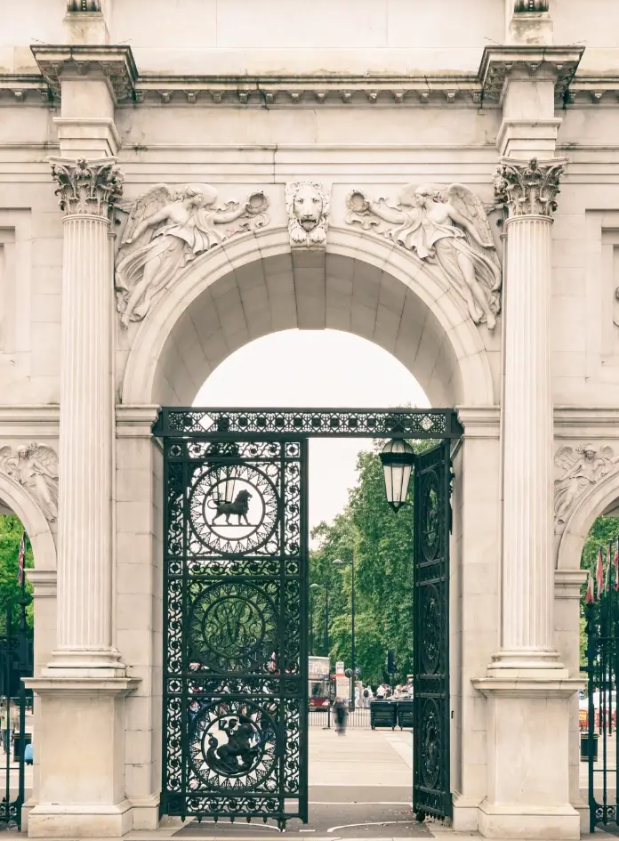 Ornate, carved white marble victory arch in London, with black wrought iron gates